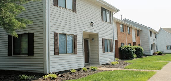 a row of houses with vinyl siding and a sidewalk in front of them