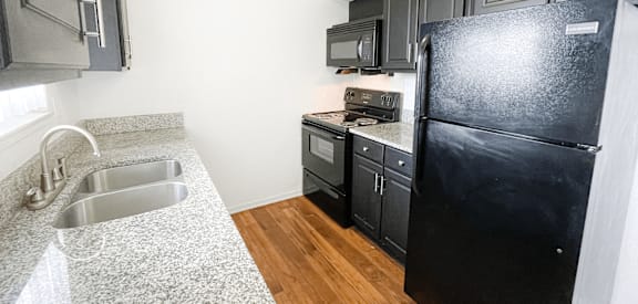 A kitchen with a black fridge and a stove top oven.