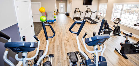 a gym with cardio machines and weights on a wood floor