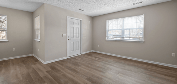 an empty living room with a door and a window