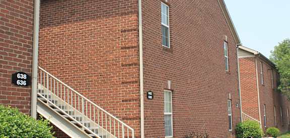 a red brick building with a staircase and trees in the background