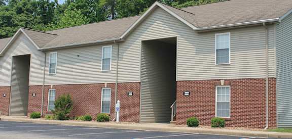 a building with a parking lot and trees in the background