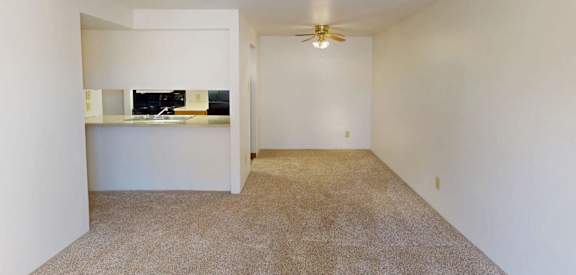 A room with a ceiling fan and carpeted floor.