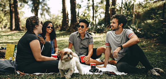 a group of people sitting in the grass with a dog