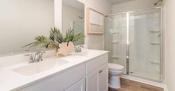 A bathroom with a white sink and a glass shower stall.