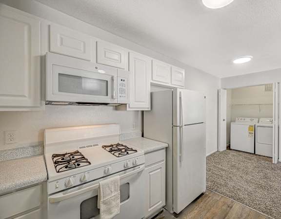 A kitchen with white cabinets and appliances.