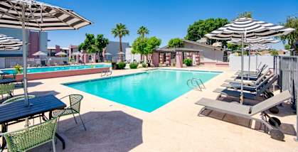 a swimming pool with chairs and umbrellas next to a resort style pool at Connect on Missour Apartments, Phoenix 85015