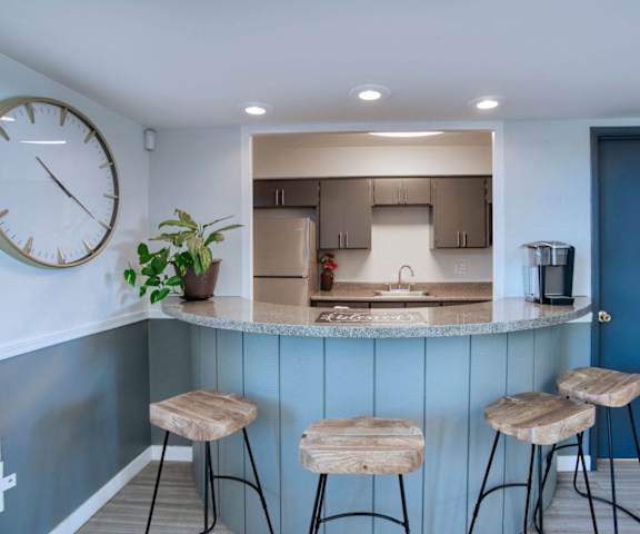 a kitchen with a counter top and three stools at Connect on Missour Apartments, Phoenix 85015