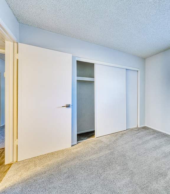 an empty room with a large window and a door to a closet at Connect on Missour Apartments, Phoenix 85015