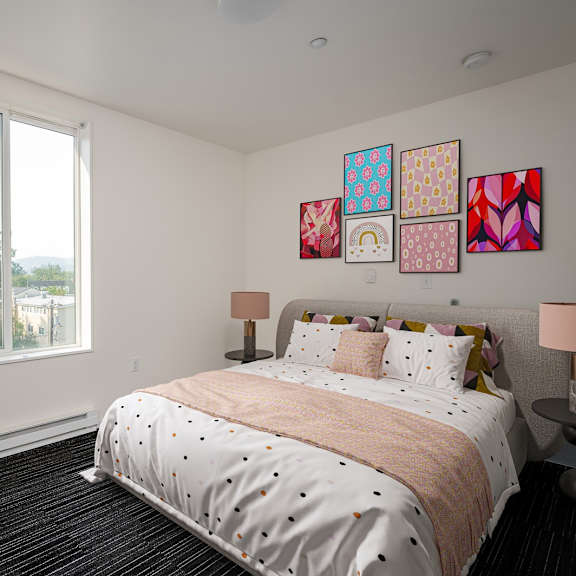 A bedroom with a large bed, a desk with a chair, and a window with a view of the outdoors.