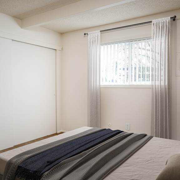 A bedroom with a bed, pillows, and a window with curtains.