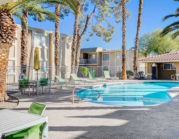 A pool surrounded by palm trees and chairs.