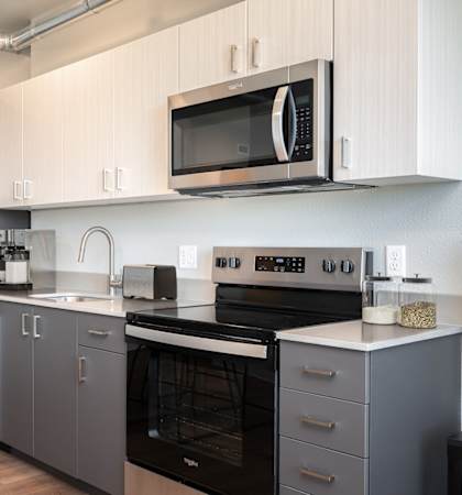 A modern kitchen with a refrigerator, oven, and microwave.