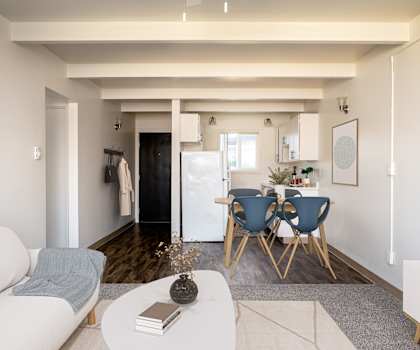 A living room with a white sofa, a grey rug, a white coffee table, a blue chair and a white cabinet.