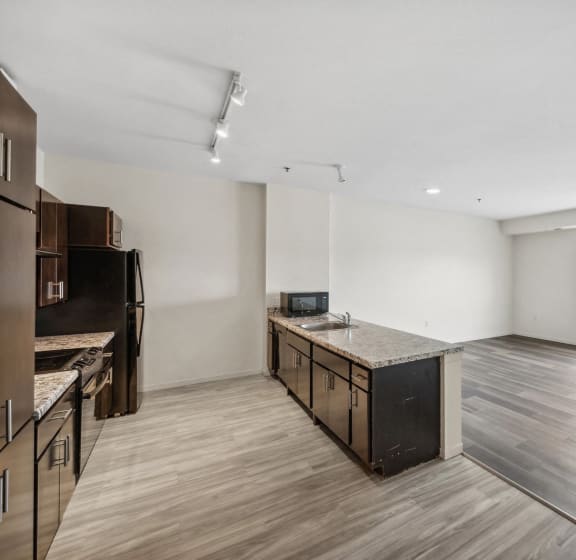 an empty living room and kitchen with wood flooring and a window