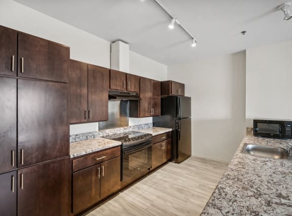 a kitchen with wooden cabinets and granite counter tops and a stainless steel refrigerator