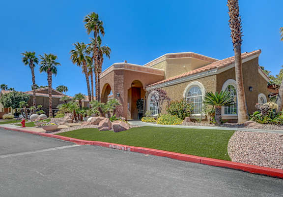 A house with a red curb and palm trees in front.