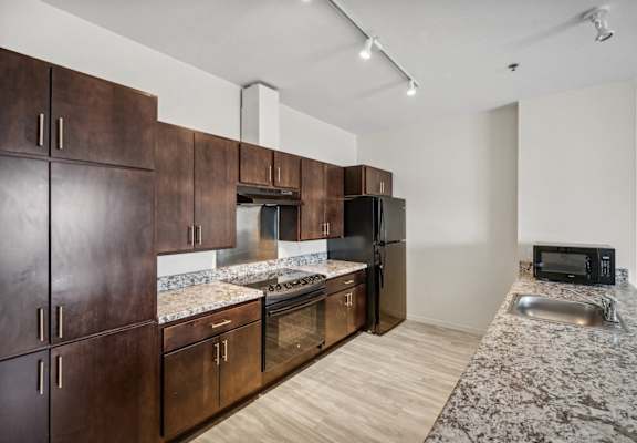 a kitchen with wooden cabinets and granite counter tops and a stainless steel refrigerator