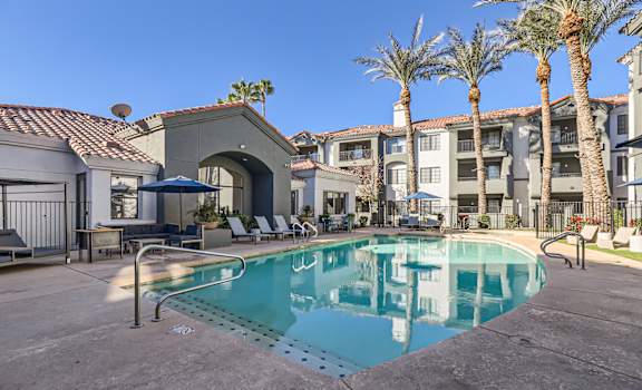 A pool in a courtyard surrounded by palm trees and buildings.