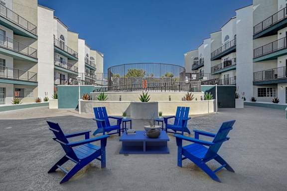 A patio with blue chairs and a table in the middle.