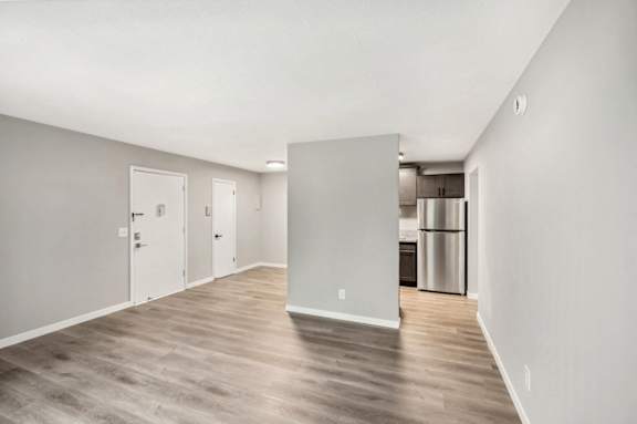 the living room and kitchen of an apartment with white walls and wood floors