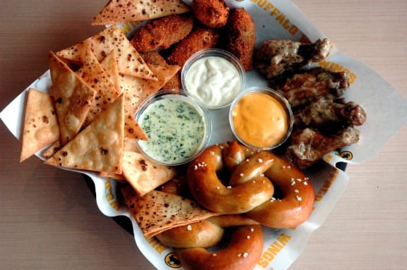 a plate of food with dips and chips and pretzels
