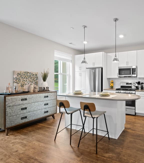 a kitchen with white cabinets and a white island with two stools at Hamilton at Eagleview, Exton, 19341
