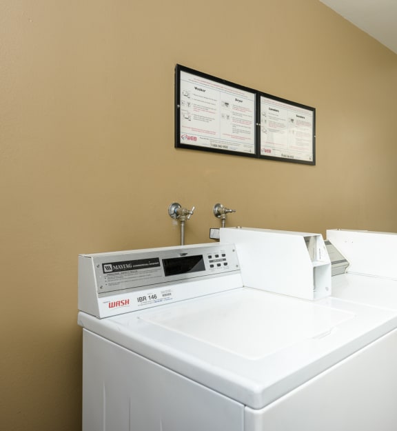 a laundry room with two washers and a dryer