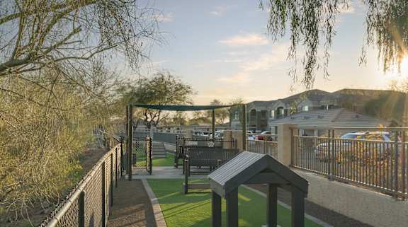 A black fence runs along a sidewalk next to a green lawn.