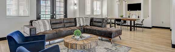 A living room with a grey couch, a blue chair and a wooden coffee table.