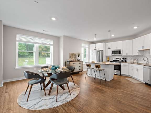 an open kitchen and dining area with a table and chairs at Hamilton at Eagleview, Pennsylvania