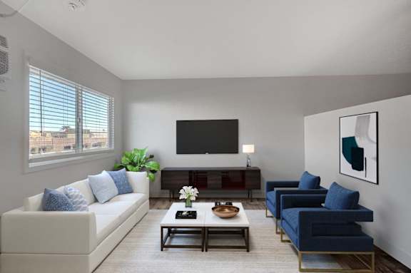 A living room with a white couch, blue chairs, and a flat screen TV.