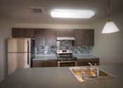 Thumbnail 3 of 6 - kitchen with stainless steel appliances, dark wood cabinets, grey patterned tile back splash, and grey counter tops