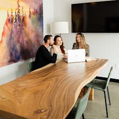 Three people sitting at a table with a laptop.