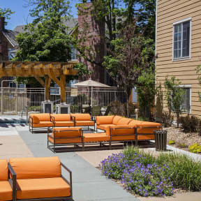 a patio with orange couches and chairs and umbrellas at Skyview Apartments, Westminster, CO 80234