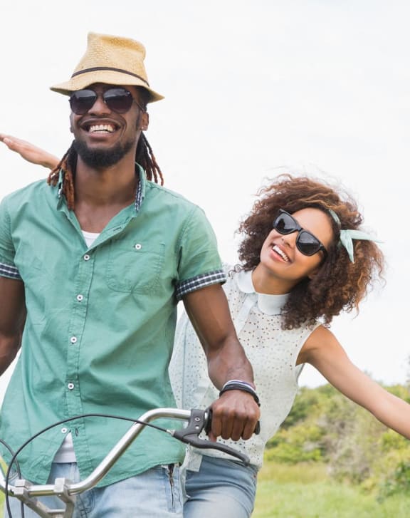a man and woman riding a bike in a field