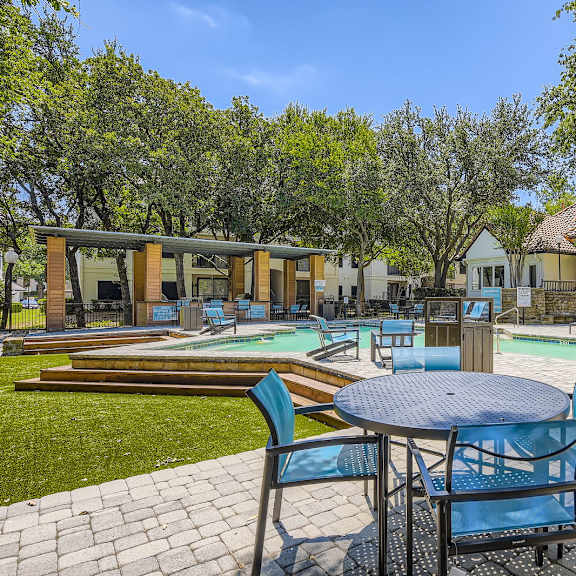 A patio with a table and chairs overlooking a pool.