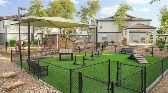 a fenced in play area with benches and umbrellas