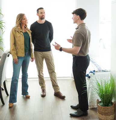 Three people are standing in a room and talking to each other.