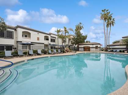 a large resort style swimming pool with buildings in the background