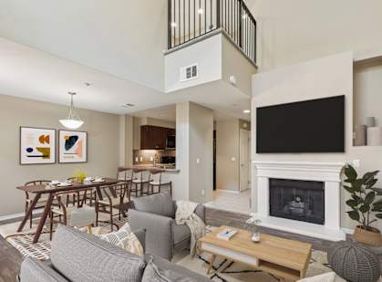 A living room with a grey couch, a wooden coffee table, a fireplace, and a television.