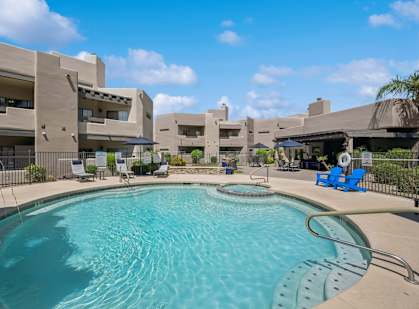 A swimming pool in front of a building with a blue sky in the background.