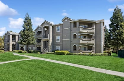 A large, modern apartment complex with a well-manicured lawn in front.