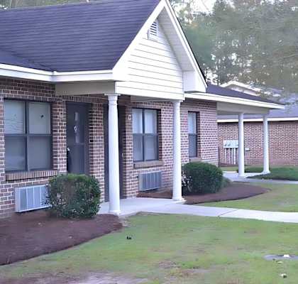 A small brick house with a porch and a white door.