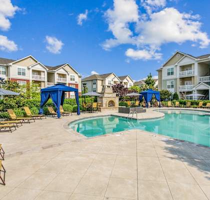 A swimming pool surrounded by lounge chairs and umbrellas in a residential area.at Century Hampton Roads, Suffolk Virginia