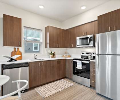 A modern kitchen with a refrigerator, microwave, oven, and sink.