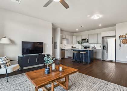 A modern living room with a wooden coffee table and a flat screen TV at Parkside at Littleton Village apartments for rent in Littleton, Colorado.