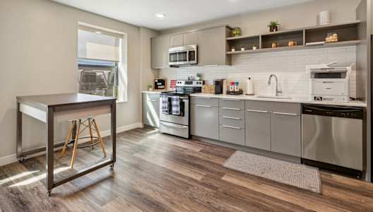 A modern kitchen with stainless steel appliances and wooden flooring.