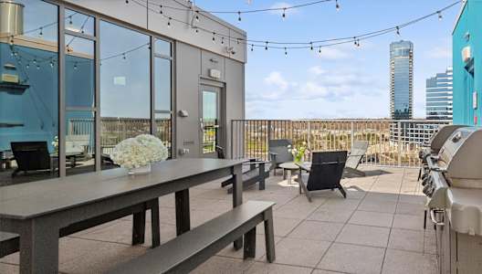 A balcony with a table and chairs overlooking a city skyline.