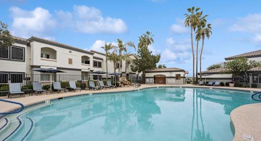 a large resort style swimming pool with buildings in the background